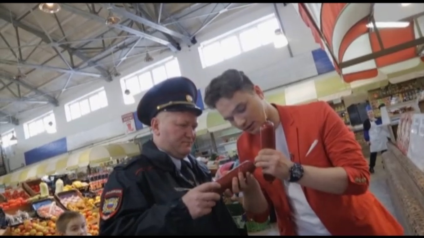 Молочко показывает переклеенную этикетку сотруднику полиции на Центральном рынке. Кадр передачи «Магаззино»